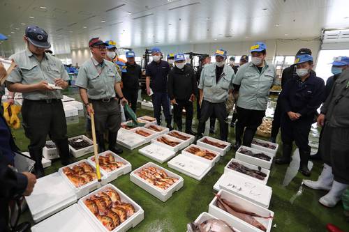 八戸みなと漁協として最後の競りを行う担当者（左側の２人）＝２０日、八戸市第３魚市場