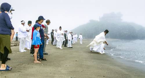 新型コロナウイルスの沈静化を願い、海に人形を流す参加者＝２８日、八戸市の蕪島海浜公園