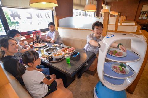 自動配膳ロボット「PEANUT」から料理を受け取る来店客=5日正午すぎ、八戸市の「炭火焼肉 悠々館」