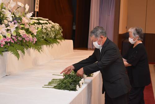 祭壇に花をささげる遺族ら