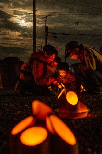 月明かりの下、境内に並んだ竹灯籠の明かりを楽しむ参拝客＝１日午後６時４５分ごろ、八戸市小中野８丁目の御前神社