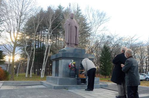 西有穆山の銅像の前で祈りをささげる参列者