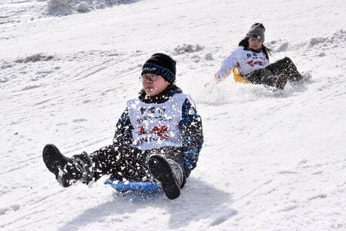そりに乗って勢いよくコースを滑る出場者